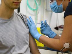 In this screen grab from video issued by Britain's Oxford University, a volunteer is injected with either an experimental COVID-19 vaccine or a comparison shot as part of the first human trials in the U.K. to test a potential vaccine, led by Oxford University in England on April 25, 2020. About 100 research groups around the world are pursuing vaccines against the coronavirus, with nearly a dozen in early stages of human trials or poised to start. (University of Oxford via AP)
