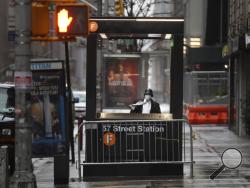 In this April 13, 2020 file photo, a man enters the subway on a rainy day in New York. New York City transit officials said they're providing buses for homeless people to shelter from unseasonably frigid temperatures this weekend during newly instituted overnight subway closures. (AP Photo/Seth Wenig, File)