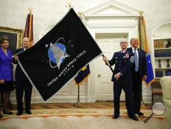 President Donald Trump stands as Chief of Space Operations at US Space Force Gen. John Raymond, second from left, and Chief Master Sgt. Roger Towberman, second from right, hold the United States Space Force flag as it is presented in the Oval Office of the White House, Friday, May 15, 2020, in Washington. Secretary of the Air Force Barbara Barrett stands far left. (AP Photo/Alex Brandon)