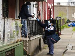 United States Postal Service carrier Henrietta Dixon delivers mail to Alvin Fields in Philadelphia, Wednesday, May 6, 2020. Fields called Dixon "absolutely wonderful." (AP Photo/Matt Rourke)