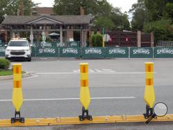 Barricades and a security vehicle block the entrance to a closed Disney Springs Monday, May 18, 2020, in Lake Buena Vista, Fla. As Walt Disney World shops and restaurants prepare to open at its entertainment complex later this week, it's posting a warning about the dangers of coronavirus advising guests that they voluntarily assume all risks related to exposure to COVID-19. (AP Photo/(John Raoux)