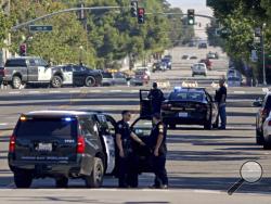 Law enforcement personnel from several jurisdictions patrol Spring Street in downtown Paso Robles, Calif., as law enforcement agencies responded to an early morning shooting in the Central Coast city after a sheriff's deputy was wounded early Wednesday, June 10, 2020. A man has been found fatally shot near where the deputy was wounded after someone opened fire on a police station. (David Middlecamp/The Tribune of San Luis Obispo via AP)