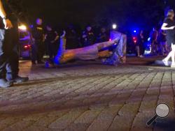In this image from video, police stand near a toppled statue of Jefferson Davis on Wednesday night, June 10, 2020, in Richmond, Va. Protesters tore down the statue of Confederate President Davis along Monument Avenue. The statue in the former capital of the Confederacy was toppled shortly before 11 p.m., news outlets reported. (WWBT-TV via AP)