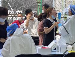 Residents line up to get tested at a coronavirus testing center set up outside a sports facility in Beijing, Tuesday, June 16, 2020. China reported several dozen more coronavirus infections Tuesday as it increased testing and lockdown measures in parts of the capital to control what appeared to be its largest outbreak in more than two months. (AP Photo/Ng Han Guan)