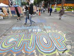 Pedestrians walk Sunday, June 21, 2020, in Seattle, where streets are blocked off in what has been named the Capitol Hill Occupied Protest (CHOP) zone. Police pulled back from several blocks of the city's Capitol Hill neighborhood near the Police Department's East Precinct building earlier in the month after clashes with people protesting the death of George Floyd. (AP Photo/Elaine Thompson)