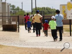 (AP Photo/Eric Gay) In this Aug. 23, 2019 file photo, immigrants seeking asylum hold hands as they leave a cafeteria at the ICE South Texas Family Residential Center in Dilley, Texas. The isolation of at least three families at the U.S. Immigration and Customs Enforcement's detention center in Dilley, has raised new fears of the coronavirus spreading through a facility that has long been accused of providing substandard medical care. 