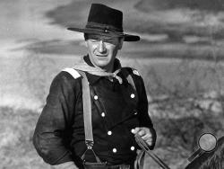 FILE - In this undated photo, John Wayne appears during the filming of "The Horse Soldiers." In the latest move to change place names in light of U.S. racial history, leaders of Orange County’s Democratic Party are pushing to drop film legend Wayne’s name, statue and other likenesses from the county’s airport because of his racist and bigoted comments. (AP Photo, File)