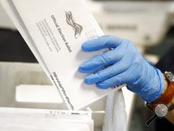 FILE - In this May 27, 2020 file photo, a worker processes mail-in ballots at the Bucks County Board of Elections office prior to the primary election in Doylestown, Pa. Deep-pocketed and often anonymous donors are pouring over $100 million into an intensifying dispute about whether it should be easier to vote by mail, a fight that could determine President Donald Trump's fate in the November election. (AP Photo/Matt Slocum, File)