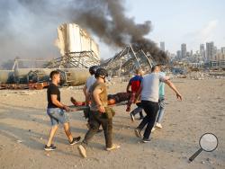 Civilians carry a victim at the explosion scene that hit the seaport, in Beirut Lebanon, Tuesday, Aug. 4, 2020. Massive explosions rocked downtown Beirut on Tuesday, flattening much of the port, damaging buildings and blowing out windows and doors as a giant mushroom cloud rose above the capital. Witnesses saw many people injured by flying glass and debris. (AP Photo/Hussein Malla)