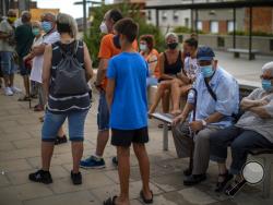 People wearing face masks wait their turn to be called for a PCR test for the COVID-19 outside a local clinic in Santa Coloma de Gramanet in Barcelona, Spain, Tuesday, Aug. 11, 2020. (AP Photo/Emilio Morenatti)