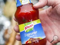 FILE- In this May 6, 2014 taken photo a man holds a bottle of "gypsy sauce" from the manufacturer Knorr in his hand in Berlin, Germany. Hauke-Christian Dittrich/dpa via AP)