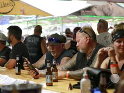 People congregates at One-Eyed Jack's Saloon during the 80th annual Sturgis Motorcycle Rally on Aug. 7, 2020, in Sturgis, South Dakota. The South Dakota Department of Health issued warnings that two people who had visited the bar may have transmitted COVID-19. (AP Photo/Stephen Groves)