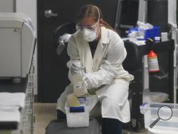 A laboratory assistant holds sewage samples collected from Utah State University dormitory's Wednesday, Sept. 2, 2020, in Logan, Utah. About 300 students are quarantined to their rooms this week, but not because anyone got sick or tested positive. Instead, the warning bells came from the sewage. Colleges around the country are monitoring wastewater in hopes of stopping coronavirus outbreaks before they get out of hand. Utah State became at least the second school to quarantine hundreds of students after sew