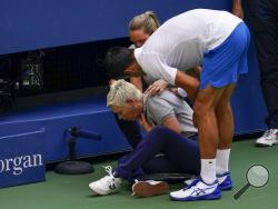 Novak Djokovic, of Serbia, checks a linesman after hitting her with a ball in reaction to losing a point to Pablo Carreno Busta, of Spain, during the fourth round of the US Open tennis championships, Sunday, Sept. 6, 2020, in New York. Djokovic defaulted the match. (AP Photo/Seth Wenig)