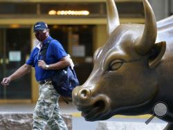A man wearing a mask passes the Charging Bull statue in New York's financial district, Tuesday, Sept. 8, 2020. More sharp declines for big tech stocks are dragging Wall Street toward a third straight loss on Tuesday. (AP Photo/Mark Lennihan)