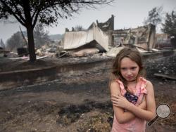 Ellie Owens, 8, from Grants Pass, Ore., looks at fire damage Friday, Sept. 11, 2020, as destructive wildfires devastate the region in Talent, Ore. (AP Photo/Paula Bronstein)