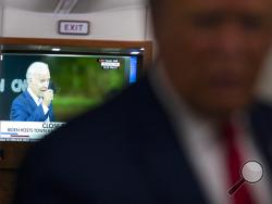 A television screen shows Democratic presidential candidate former Vice President Joe Biden holding up a mask, as President Donald Trump talks with reporters on Air Force One while returning to Washington after a campaign rally at Central Wisconsin Airport, Thursday, Sept. 17, 2020. (AP Photo/Evan Vucci)