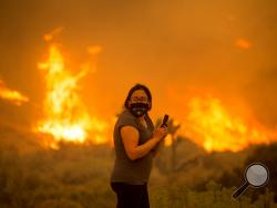 A woman watches as the Bobcat Fire burns in Juniper Hill, Calif., Friday, Sept. 18, 2020. (AP Photo/Ringo H.W. Chiu)