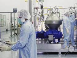 In this undated image from video provided by Regeneron Pharmaceuticals on Friday, Oct. 2, 2020, scientists work with a bioreactor at a company facility in New York state, for efforts on an experimental coronavirus antibody drug. Antibodies are proteins the body makes when an infection occurs; they attach to a virus and help the immune system eliminate it. (Regeneron via AP)