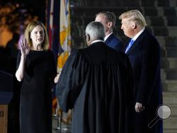 President Donald Trump watches as Supreme Court Justice Clarence Thomas administers the Constitutional Oath to Amy Coney Barrett on the South Lawn of the White House in Washington, Monday, Oct. 26, 2020, after Barrett was confirmed by the Senate earlier in the evening. (AP Photo/Patrick Semansky)