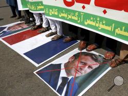 Supporters of the Muslims Students Organization stand on a representation of a French national flag and defaced images of French President Emmanuel Macron during a protest against the president and against the publishing of caricatures of the Prophet Muhammad they deem blasphemous, in Karachi, Pakistan, Friday, Oct. 30, 2020. Muslims have been calling for both protests and a boycott of French goods in response to France's stance on caricatures of Islam's most revered prophet. (AP Photo/Fareed Khan)