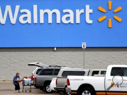 FILE - In this March 31, 2020 file photo, a woman pulls groceries from a cart to her vehicle outside of a Walmart store in Pearl, Miss. Walmart has reversed course, announcing Friday, Oct. 30 it is returning ammunition and firearms to their displays in its U.S. stores. The nation’s largest retailer had previously said it had removed the items from displays due to “civil unrest” in some areas of the country but said Friday the items had been restored to displays because the unrest has remained isolated. (AP 