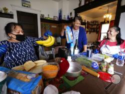 Olga Garcia, left, and her sisters Francis Garcia, center, and Anna Garcia work to prepare an afternoon family meal Wednesday, Nov. 4, 2020, in the family home in Sedro-Woolley, Wash. On any other Thanksgiving, dozens of Olga's family members would squeeze into her home for the holiday. But this year, she'll deliver food to family spread along 30 miles of the North Cascades Highway in Washington state. If the plan works, everyone will sit down to eat in their own homes at precisely 6:30 p.m. and join a grou