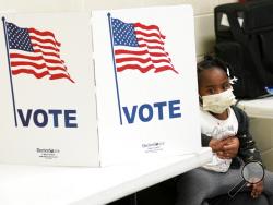 In this Nov. 3, 2020, photo, Mikara Stewart, 5, looks around a voting privacy kiosk while her unseen grandmother Doris Thomas, votes in Precinct 36 after standing in line for almost two hours in Jackson, Miss. The 2020 presidential election officially entered the record books Saturday the turnout reached 61.8%, eclipsing the recent mark set by Barack Obama's first presidential campaign in 2008 and demonstrating the extraordinary engagement of Americans in the referendum on Donald Trump's presidency. (AP Pho