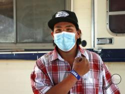 In this Oct. 19, 2020 photo, Cuba High School senior Cyliss Castillo shows off his slap bracelet USB drive loaded with assignments that was delivered by school bus driver Kelly Maeastas, outside Cuba, New Mexico. The closing of classrooms and the switch to remote learning because of the coronavirus outbreak have left Castillo and other students in this school district on the sparsely populated fringe of the Navajo Nation in New Mexico profoundly isolated, cut off from other people — and, in many cases, the 