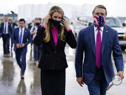FILE- In this July 15, 2020, file photo Sen. Kelly Loeffler, R-Ga., puts on a face mask as she walks with Sen. David Perdue, R-Ga., right, at UPS Hapeville Airport Hub in Atlanta. (AP Photo/Evan Vucci, File)