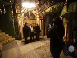 Christians take photos inside the Grotto of the Church of the Nativity, traditionally believed to be the birthplace of Jesus Christ, in the West Bank city of Bethlehem, Monday, Nov. 23, 2020. Normally packed with tourists from around the world at this time of year, Bethlehem resembles a ghost town – with hotels, restaurants and souvenir shops shuttered by the pandemic. (AP Photo/Majdi Mohammed)