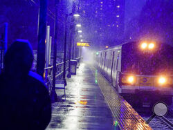 A woman waits for a Long Island Rail Road train in the Queens borough of New York as snow falls at the start of an oncoming snow storm, Wednesday, Dec. 16, 2020. (AP Photo/Frank Franklin II)