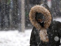 FILE - In this Dec. 17, 2020, file photo, a woman walks through a snowstorm in the Bronx borough of New York. (AP Photo/Mark Lennihan, File)