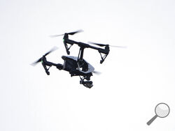 FILE - In this Thursday, Aug. 8, 2019, file photo, a drone flies in a residential neighborhood in Upper Moreland, Pa. Federal officials are outlining new rules that will let operators fly small drones over people and at night. (AP Photo/Matt Rourke, File)