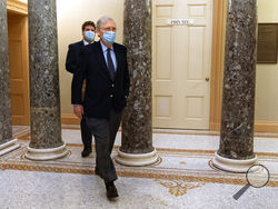 Followed by a staffer, Senate Majority Leader Mitch McConnell of Ky., right, leaves the Capitol for the day, Tuesday, Dec. 29, 2020, on Capitol Hill in Washington. (AP Photo/Jacquelyn Martin)