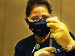 Houston Health Department LVN Alicia Meza prepares a dose of COVID-19 vaccine Sunday, Jan. 3, 2021, at a Houston Health Department's COVID-19 vaccine clinic in Houston. The department vaccinated 1,008 people who qualify under Phase 1A or Phase 1B of the state's guidelines at the clinic's first day on Saturday. (Yi-Chin Lee/Houston Chronicle via AP)
