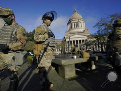 Members of the Washington National Guard stand at a sundial near the Legislative Building, Sunday, Jan. 10, 2021, at the Capitol in Olympia, Wash. Governors in some states have called out the National Guard, declared states of emergency and closed their capitols over concerns about potentially violent protests. (AP Photo/Ted S. Warren)