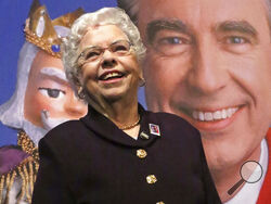 FILE - Joanne Rogers stands in front of a giant Mister Rogers Forever Stamp following the first-day-of-issue dedication in Pittsburgh on March 23, 2018. Rogers, the widow of Fred Rogers, the gentle TV host who entertained and educated generations of preschoolers on “Mister Rogers’ Neighborhood,” has died. She was 92. (AP Photo/Gene J. Puskar, File)