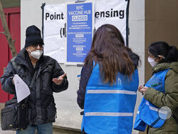 A man who came to get a COVID-19 vaccine holds his paperwork as he talks to a New York City health department worker outside a closed vaccine hub, Thursday, Jan. 21, 2021, in the Brooklyn borough of New York. Public health experts are blaming COVID-19 vaccine shortages around the U.S. in part on the Trump administration's push to get states to vastly expand their vaccination drives to reach the nation's estimated 54 million people age 65 and over. The push that began over a week ago has not been accompanied