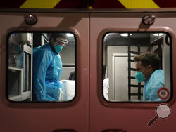 Emergency medical technician Thomas Hoang, left, of Emergency Ambulance Service, and paramedic Trenton Amaro prepare to unload a COVID-19 patient from an ambulance in Placentia, Calif., Friday, Jan. 8, 2021. EMTs and paramedics have always dealt with life and death — they make split-second decisions about patient care, which hospital to race to, the best and fastest way to save someone — and now they're just a breath away from becoming the patient themselves. (AP Photo/Jae C. Hong)