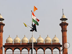 A Sikh man hangs on to a pole holding a Sikh religious flag along with a farm union flag at the historic Red Fort monument in New Delhi, India, Tuesday, Jan. 26, 2021. Tens of thousands of protesting farmers drove long lines of tractors into India's capital on Tuesday, breaking through police barricades, defying tear gas and storming the historic Red Fort as the nation celebrated Republic Day. (AP Photo/Supreet Sapkal)