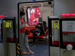 Commuters wearing face masks to help curb the spread of the coronavirus browse their smartphones inside a subway train in Beijing Wednesday, Feb. 10, 2021. China's internet watchdog is cracking down further on online speech, issuing a new requirement that bloggers and influencers have a license before they can publish on certain topics. The rule from the Cyberspace Administration of China that goes into effect later this month is shrinking an already highly limited space for discourse amid heavy censorship 