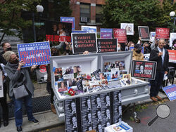 FILE - In this Sunday, Oct. 18, 2020 file photo, families of COVID-19 victims who passed away in New York nursing homes gather in front of the Cobble Hill Heath Center in the Brooklyn borough of New York, to demand New York State Gov. Andrew Cuomo's apologize for his response to clusters in nursing homes during the pandemic. More than 9,000 recovering coronavirus patients in New York state were released from hospitals into nursing homes at the height of the pandemic under a controversial order that was scra