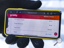 DeAndré Upshaw shows a $5,000 bill from Griddy on his cell phone for his 900-square-foot apartment during very cold weather in Dallas, on Friday, Feb. 19, 2021. The Texas power supplier Griddy, which sells unusual plans with prices tied to the spot price of power on the Texas grid, warned its customers over the weekend that their bills would rise significantly during the storm and that they should switch providers. (Lola Gomez//The Dallas Morning News via AP)