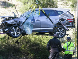 A crane is used to lift a vehicle following a rollover accident involving golfer Tiger Woods, Tuesday, Feb. 23, 2021, in the Rancho Palos Verdes suburb of Los Angeles. Woods suffered leg injuries in the one-car accident and was undergoing surgery, authorities and his manager said. (AP Photo/Ringo H.W. Chiu)