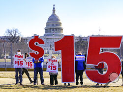 Activists appeal for a $15 minimum wage near the Capitol in Washington, Thursday, Feb. 25, 2021. The $1.9 trillion COVID-19 relief bill being prepped in Congress includes a provision that over five years would hike the federal minimum wage to $15 an hour. (AP Photo/J. Scott Applewhite)