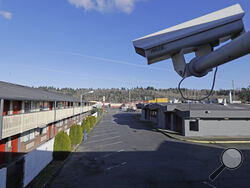 FILE - In this March 4, 2020 file photo, a security camera is shown on the second floor of a row of rooms at a motel in Kent, Wash. Hackers aiming to call attention to the dangers of mass surveillance said they were able to peer into hospitals, schools, factories, jails and corporate offices after they broke into the systems of a security-camera startup. That California startup, Verkada, said Wednesday, March 10, 2021, it is investigating the scope of the breach, first reported by Bloomberg, and has notifie