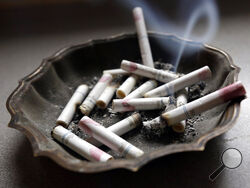 FILE - In this Saturday, March 2, 2013 file photo, a cigarette burns in an ashtray in Hayneville, Ala. Anti-smoking advocates are warning that the stress and disruptions of the COVID-19 pandemic may have slowed efforts to get more Americans to quit in 2020. (AP Photo/Dave Martin)