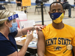 Kent State University student Marz Anderson gets his Johnson & Johnson COVID-19 vaccination from Kent State nurse Beth Krul in Kent, Ohio, Thursday, April 8, 2021. U.S. colleges hoping for a return to normalcy next fall are weighing how far they should go in urging students to get the COVID-19 vaccine, including whether they should — or legally can — require it. (AP Photo/Phil Long)
