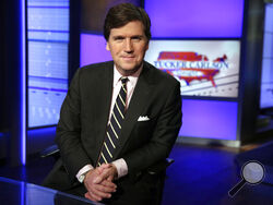 FILE - In this Thursday, March 2, 2107 file photo, Tucker Carlson, host of "Tucker Carlson Tonight," poses for a photo in a Fox News Channel studio in New York. The Anti-Defamation League has called for Fox News to fire prime-time opinion host Tucker Carlson because he defended a white-supremacist theory that says whites are being “replaced” by people of color. In a letter to Fox News CEO Suzanne Scott on Friday, April 9, 2021the head of the ADL, Jonathan Greenblatt, said Carlson's “rhetoric was not just a 